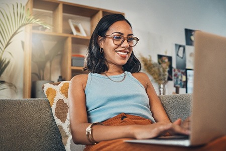 Woman smiling while working on laptop at home