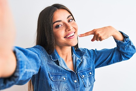 Smiling woman pointing to her white teeth