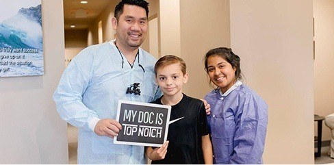 Dentist team member and young patient smiling together