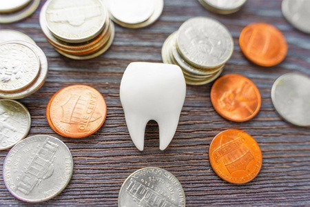 a tooth and coins representing cost of dental crowns