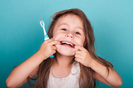 Little girl smiles with toothbrush