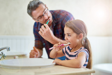 Father and daughter brush teeth