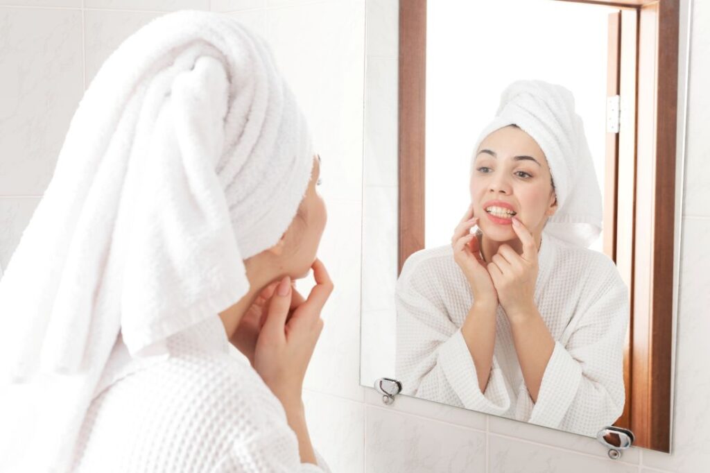 A woman looking in the mirror at her teeth.