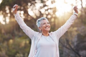 Woman smiling with arms lifted outdoors. 